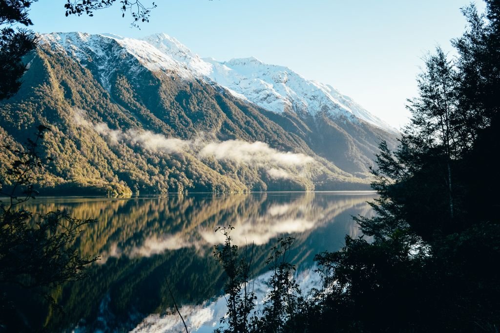 Breathtaking view of snow-capped mountains reflecting in a serene lake in Southland, New Zealand.